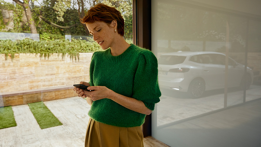 Žena drži pametni telefon BMW Service Inclusive