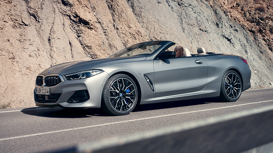 BMW M850i xDrive Kabriolet G14 LCI Facelift 2022 BMW Individual Frozen Pure siva metalik boja tročetvrtinski prednji prikaz vozila tokom vožnje s stenama u pozadini