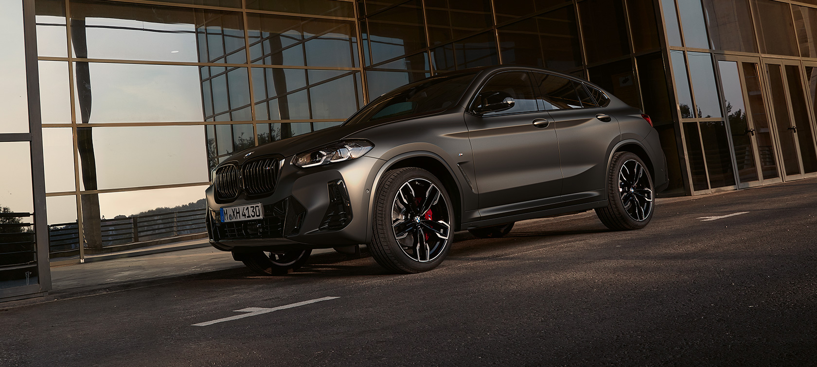 BMW X4 M40i G02 LCI Facelift tročetvrtinski prednji prikaz ispred staklene fasade