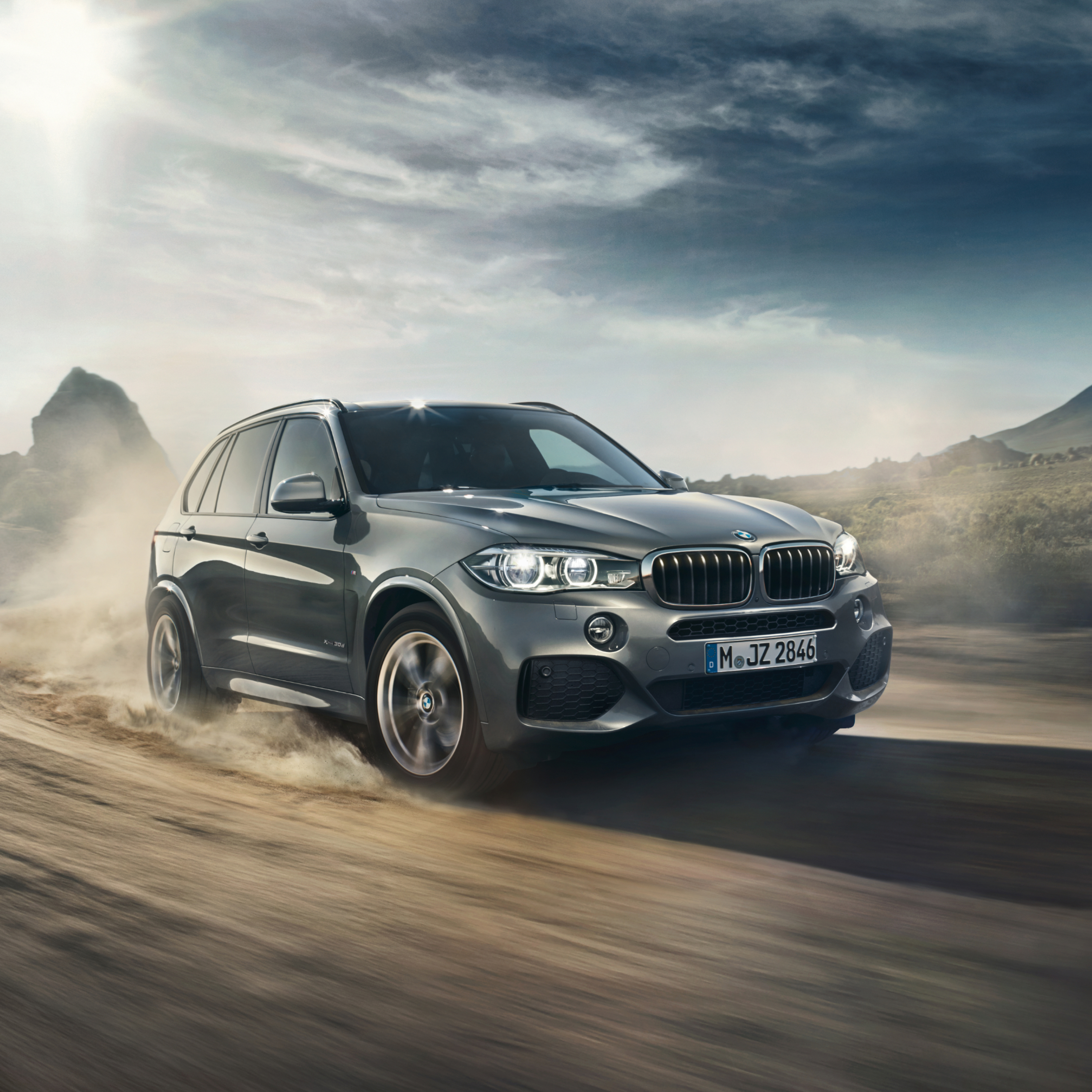 BMW X5 F15 SUV ostavlja trag prašine iza sebe tokom vožnje na stazi u divljini