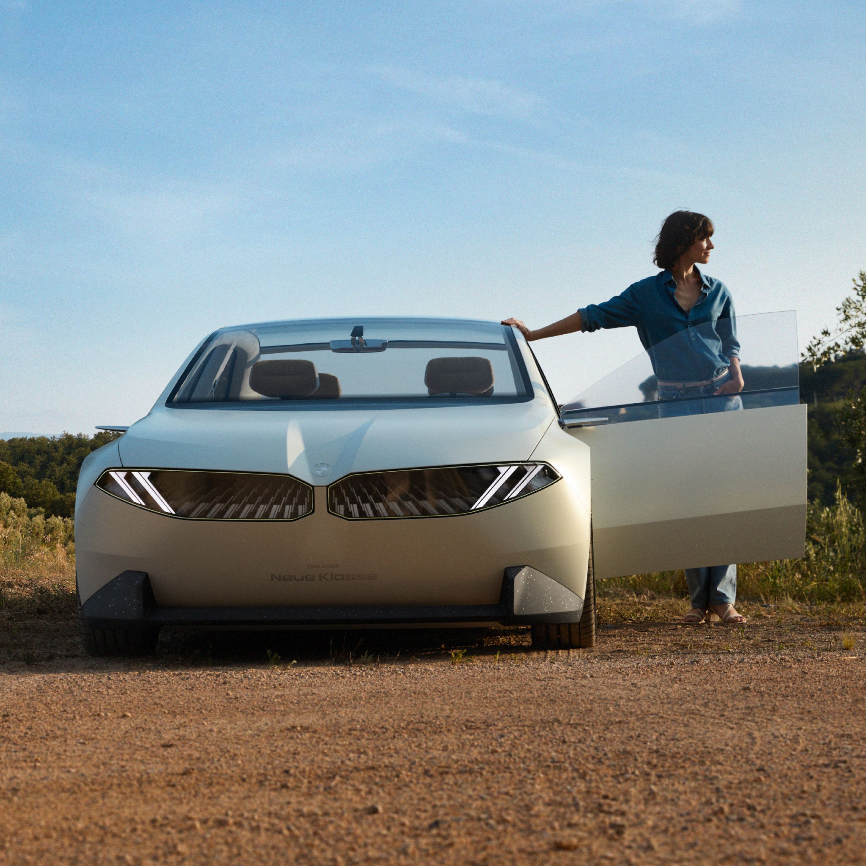 BMW Vision Nova klasa Konceptno vozilo 2023, spoljašnjost, prednji prikaz, vozilo parkirano u pustinji, otvorena vrata, sa ženom u kadru