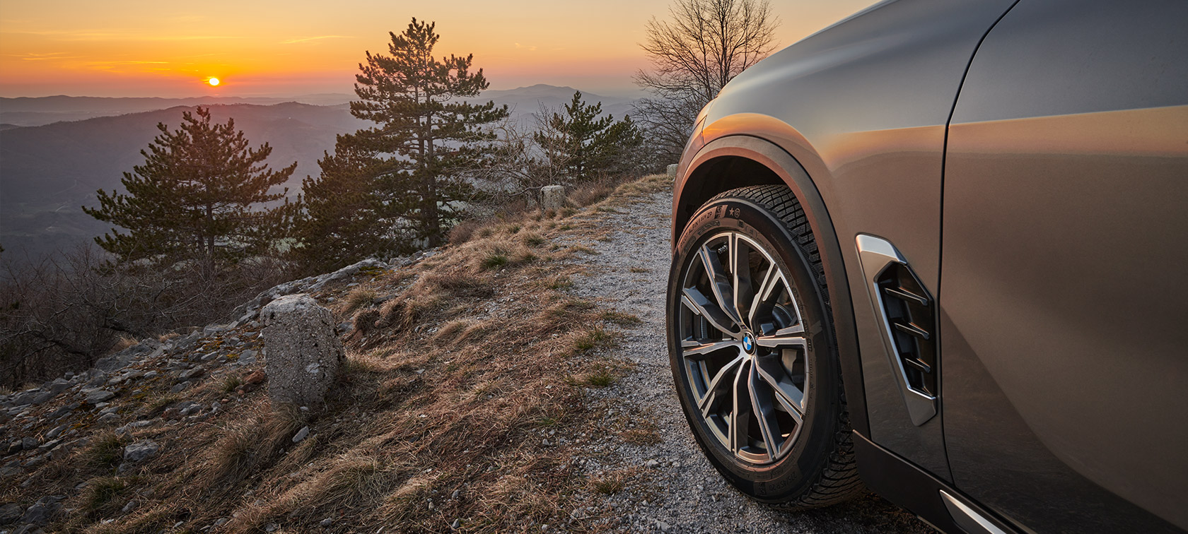 Originalni BMW točkovi na BMW X5 (G05 LCI) na putu sa planinama u pozadini i zalaskom sunca